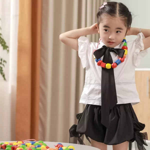 Момиче носи гердан от големи дървени мъниста Viga Toys в ярки цветове 3+