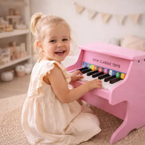 Дете свири на детско пиано от New Classic Toys в розов цвят