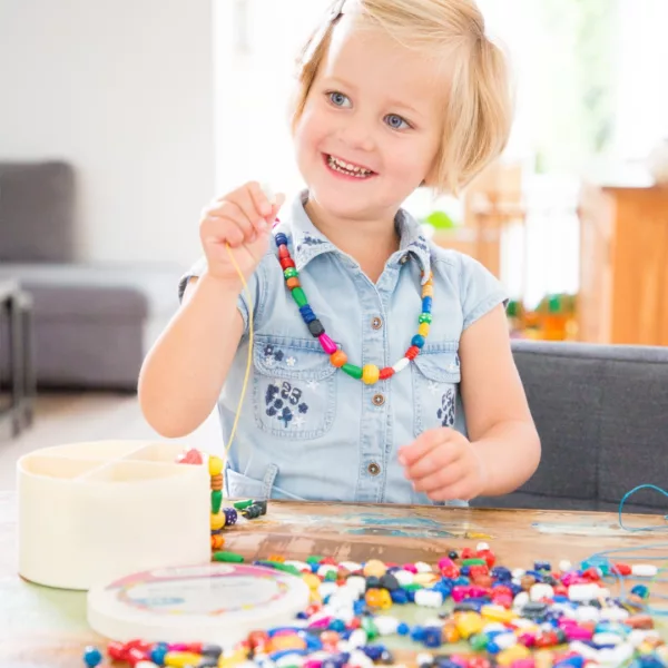 Дете нанизва цветни дървени мъниста от комплект New Classic Toys 260 гр