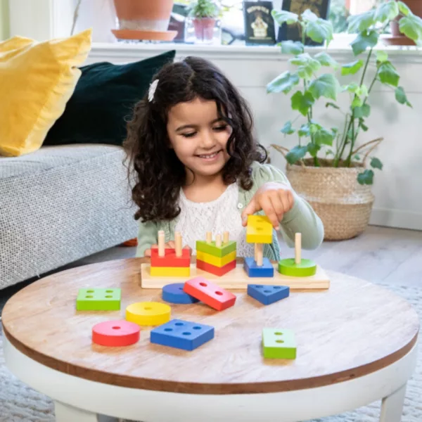 Дете играе с дървени геометрични фигури за сортиране New Classic Toys у дома
