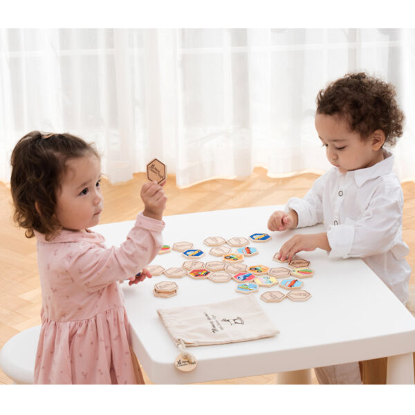 Мемори игра с транспортни средства от New Classic Toys – деца играят с дървени плочки на бяла маса