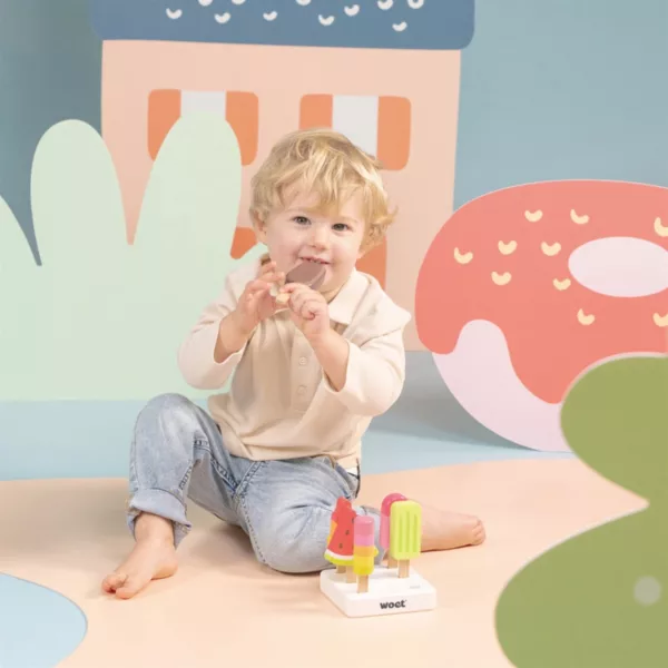 Дете играе с дървени сладоледени близалки New Classic Toys за детска сладкарница 3+