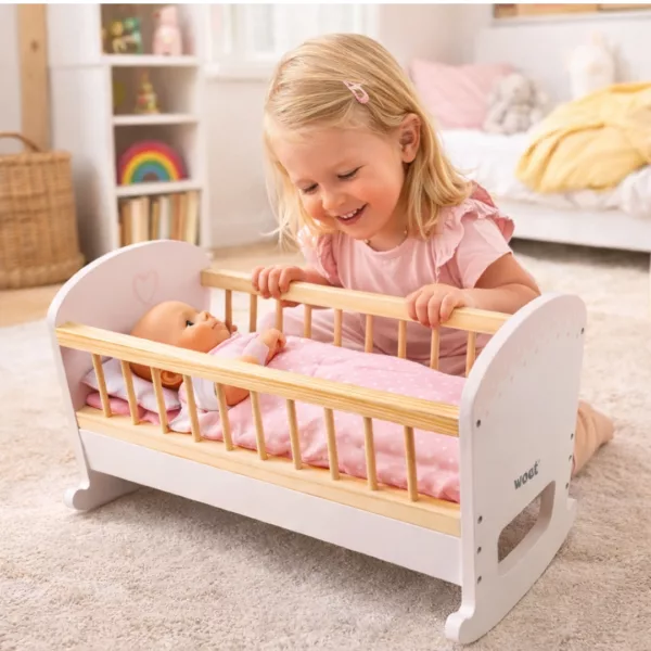 Дете играе с дървено люлеещо се легло за кукли New Classic Toys