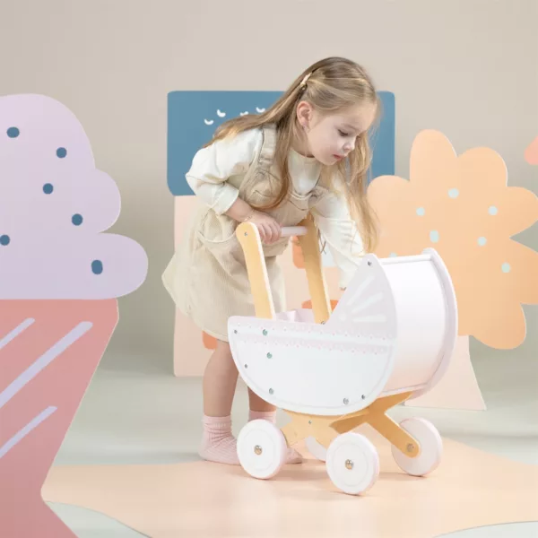 Дете играе с дървена количка за кукли в розово New Classic Toys