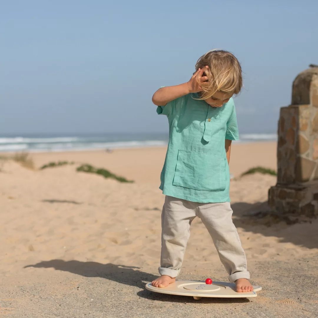 Дете играе с дървена дъска за баланс BS Toys на плажа