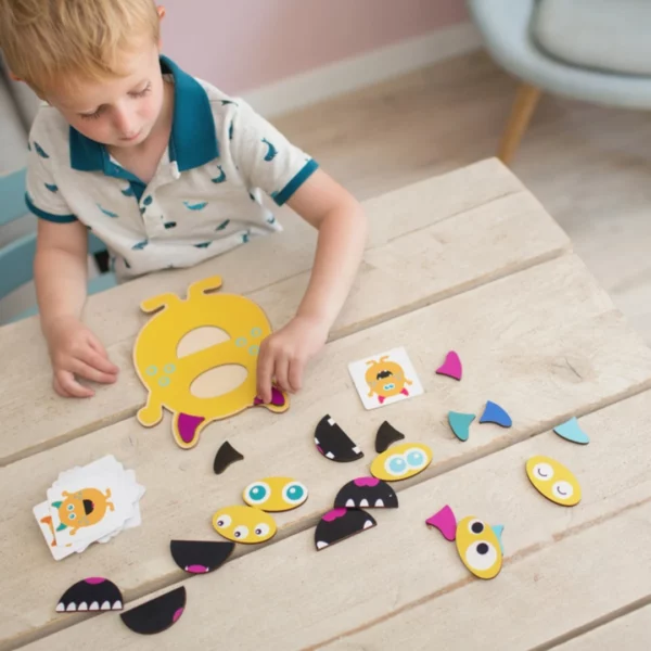 Малко момче с къса руса коса в шарена поло тениска, играещо с комплекта Чудовища близнаци