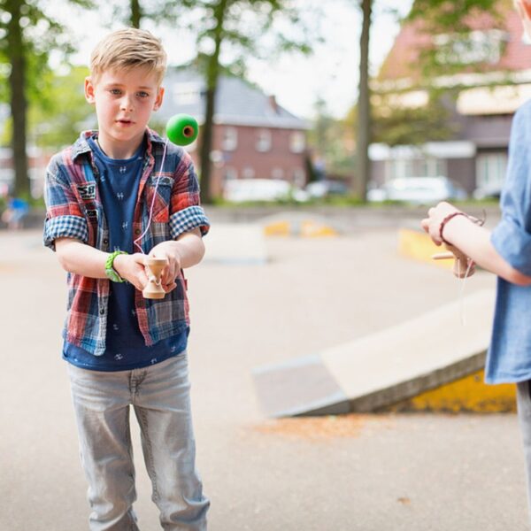 Момче играе с дървена кендама в парка