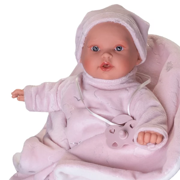 Говорещо бебе Кика с биберон и одеяло - меко тяло и звуков механизъм, 27 см, облечено в розов плюшен гащеризон и шапка, с биберон на връзка, седнало на розово одеяло.