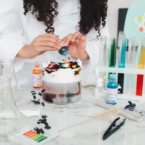 Момиче експериментира с цветни разтвори от химичен комплект Thames and Kosmos
