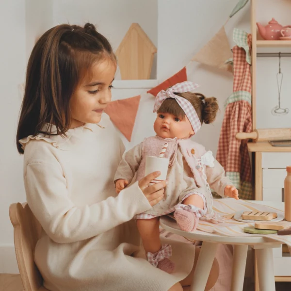 Момиче играе с реалистична кукла Бени с карирана панделка в детска кухня