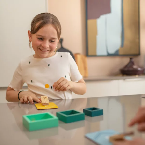 Дете играе с дървена игра за изстрелване на чипове и уцелване на мишени за забавление и учене