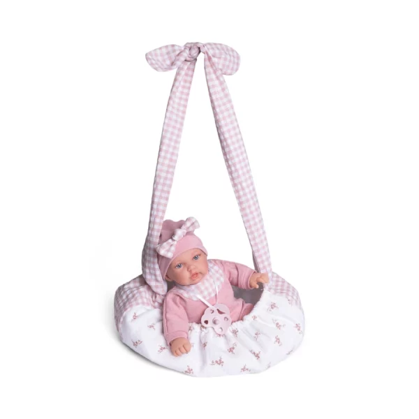Кукла бебе Рая с розов сак за носене – меко тяло и биберон, 27 см, поставена в специалния текстилен сак с розово-бели орнаменти и дълги дръжки.