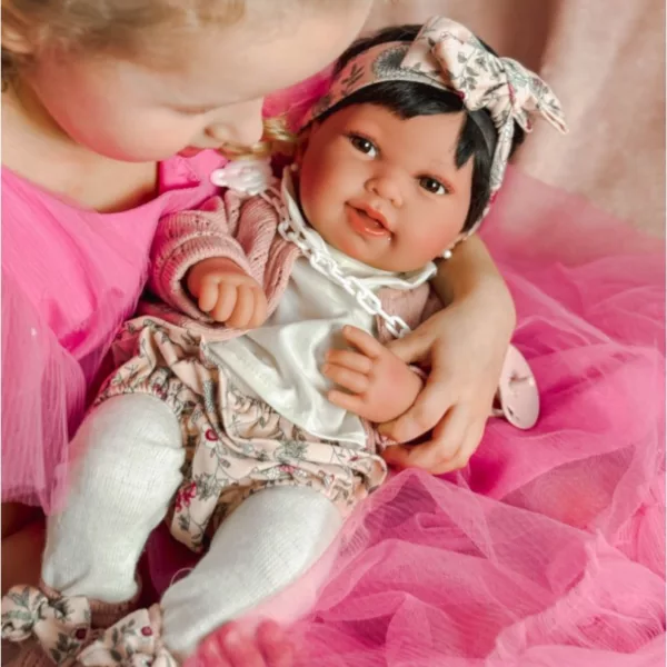 Малко момиченце прегръща своята кукла бебе Пипа с розово облекло и лента