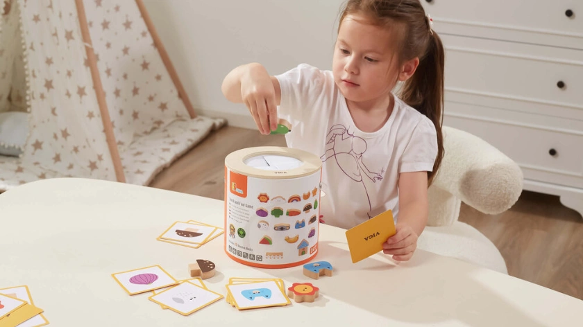 Момиче пуска карта в цилиндрична кутия като част от сензорна образователна игра за памет и концетрация