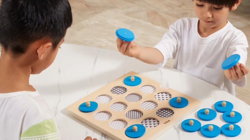 Две момчета играят с дървена дъска за памет и концетрация с примерни карти