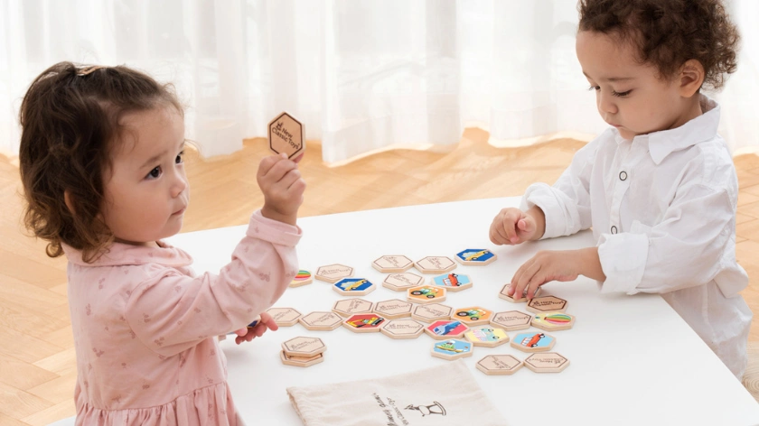 Малки деца играят с дървени шестоъгълни плочки с различни изображения, докато тренират фината моторика и паметта си