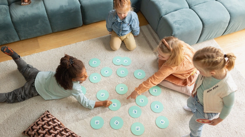 Деца играят образователна мемори игра със сладкиши на цветни кръгчета на пода.