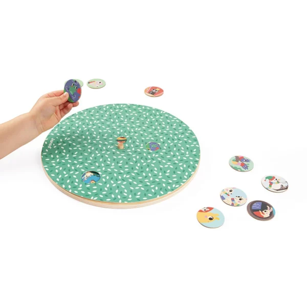 Зелена кръгла дъска с отвори и детска ръка, държаща малък кръгъл елемент от образователния пъзел "Четири сезона в градината".