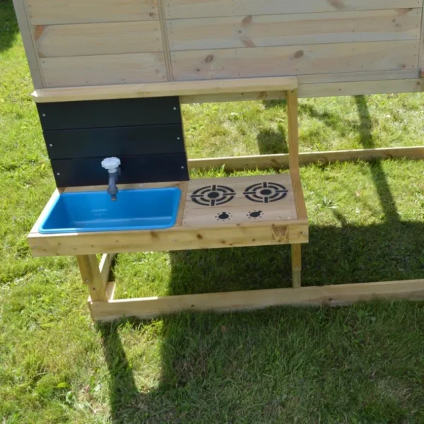 Детска площадка Wendi Toys с кухня - дървеният игрален комплекс и монтираният в него кухненски модул върху зелена трева в двора