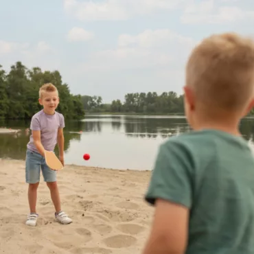 Деца играят с дървени ракети за топка на плажа с BS Toys