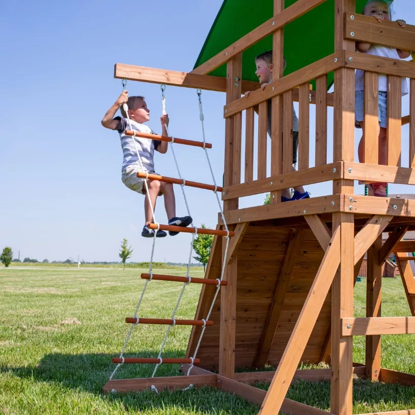 Момче се катери по въжена стълба на детска площадка Grayson Backyard с въжени катерушки.