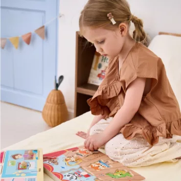 Момиче подрежда дървен пъзел с животни, образователен детски пъзел, развива фината моторика