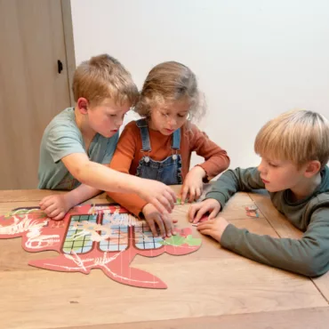 Деца редят картонен пъзел динозавър, образователна игра за групова игра, развива логика и работа в екип