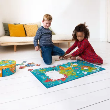 Момче и момиче подреждат голям картонен пъзел карта, образователна и забавна играчка за деца