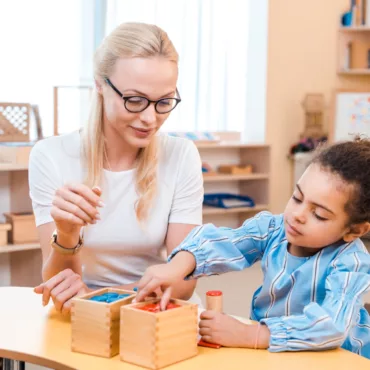 Учителка и дете играят с дървени монтесори кутии за сортиране и развиване на логика