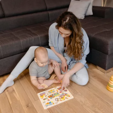 Мама и бебе подреждат дървен пъзел с дръжки, ранно развитие на моториката