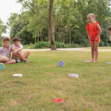 Деца играят с дървени дискове на открито, развиващи точност и концентрация в семейни игри