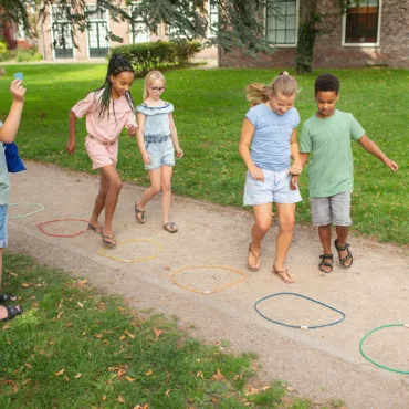 Деца играят с цветни обръчи за баланс и ловкост в парк, забавна семейна активност