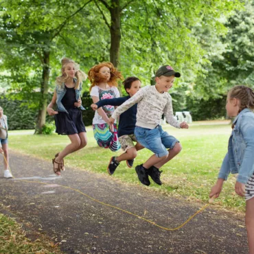 Деца скачат на въже в парка, групова спортна игра за координация и забавление на открито