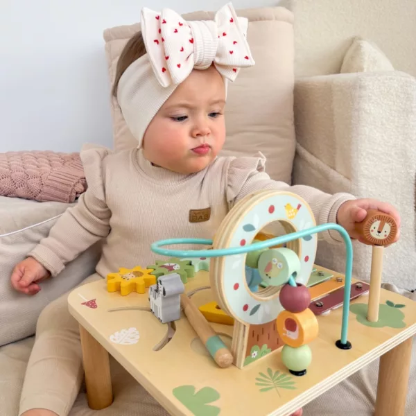 Момиченце играе с дървена активна маса с горски животни и моторна спирала