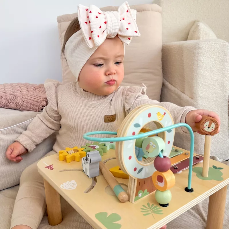 Момиченце играе с дървена активна маса с горски животни и моторна спирала