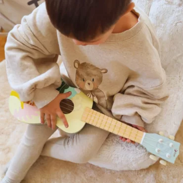 Момче свири на детска дървена китара, пастелен дизайн, класически струнен инструмент, 3+ години