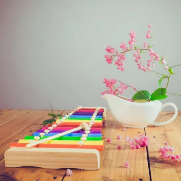 Детски ксилофон с цветни метални пластини, дървен корпус, декор с розови цветя, подходящ за деца.