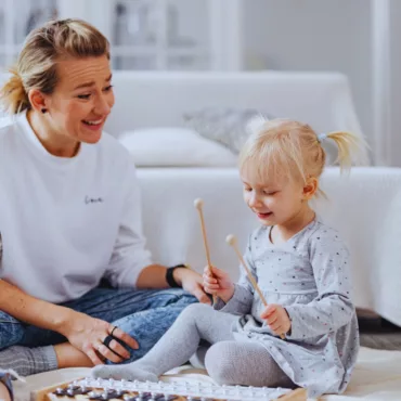 Майка и дете свирят заедно на детски металофон, дървена рамка, образователна играчка за деца.