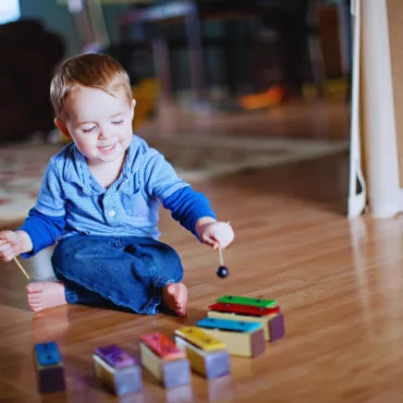 Малко момче свири на цветен детски ксилофон, дървена основа, подходящ за деца над 2 години.