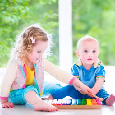 Две деца свирят на цветен детски ксилофон, дървена рамка, подходящ за развитие на слуха.
