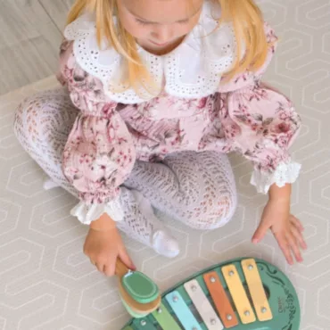 Момиче свири на дървен ксилофон в пастелни цветове, музикален комплект за деца, безопасен, подходящ за 1+ години