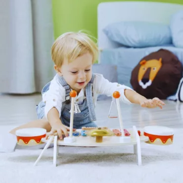 Малко момиченце с дървен музикален комплект: ксилофон, тамбурина и чинел, пастелни цветове, 1+ години