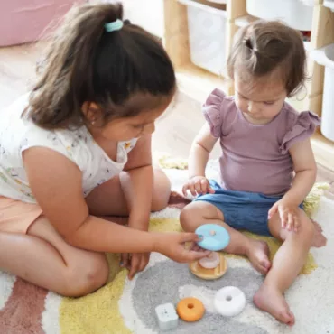 Две деца редят рингове на дървена основа, образователна бебешка играчка за развитие на моторика и концентрация