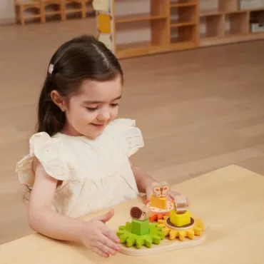 Момиче играе с дървен зъбен механизъм, бебешка образователна играчка, развиваща логика и сръчност