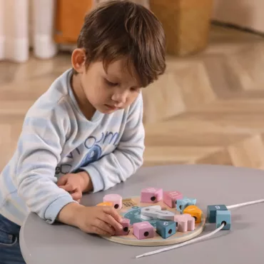 Момче подрежда дървени мъниста върху платформа, бебешка образователна играчка, рингове и сортери