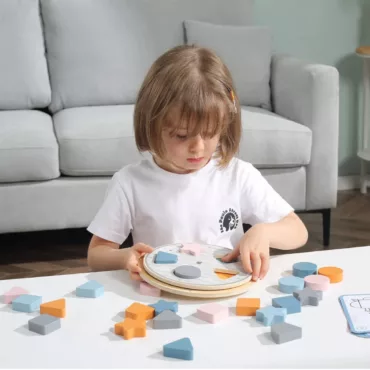 Момиче играе с дървен сортер за форми и цветове, образователна бебешка играчка за подреждане