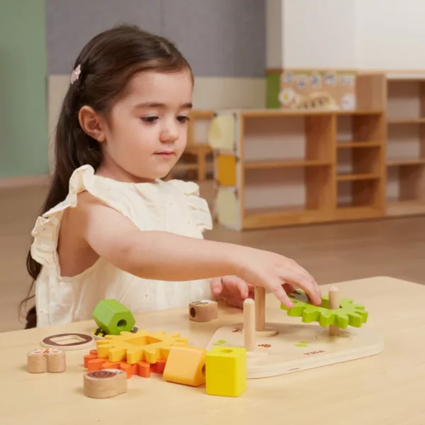 Дървен сортер с геометрични форми и зъбни колела Viga toys, момиченце играе с усмивка