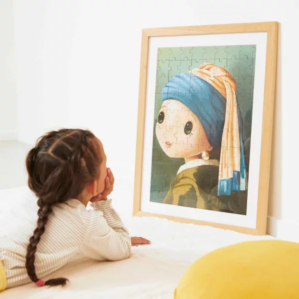 Дете разглежда рамкиран пъзел 100 части вдъхновен от Вермеер на Janod