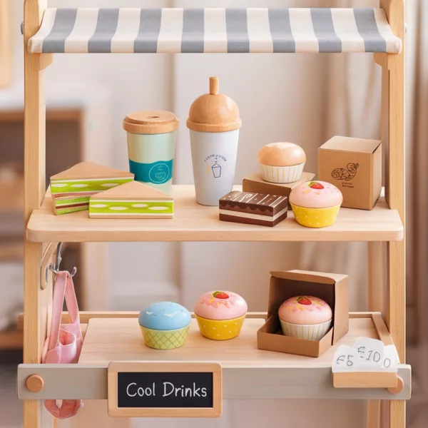 Дървен комплект кафе и сладки изкушения подреден на детски щанд с напитки и десерти.