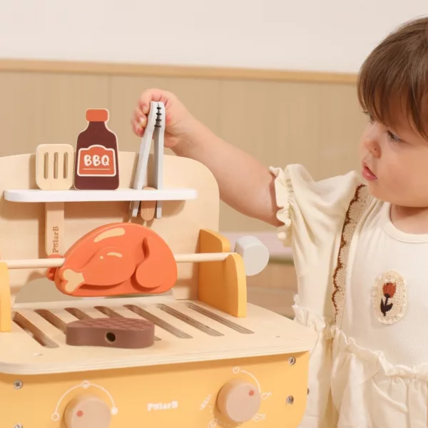 Дете използва щипките от дървен барбекю комплект PolarB до грил печка